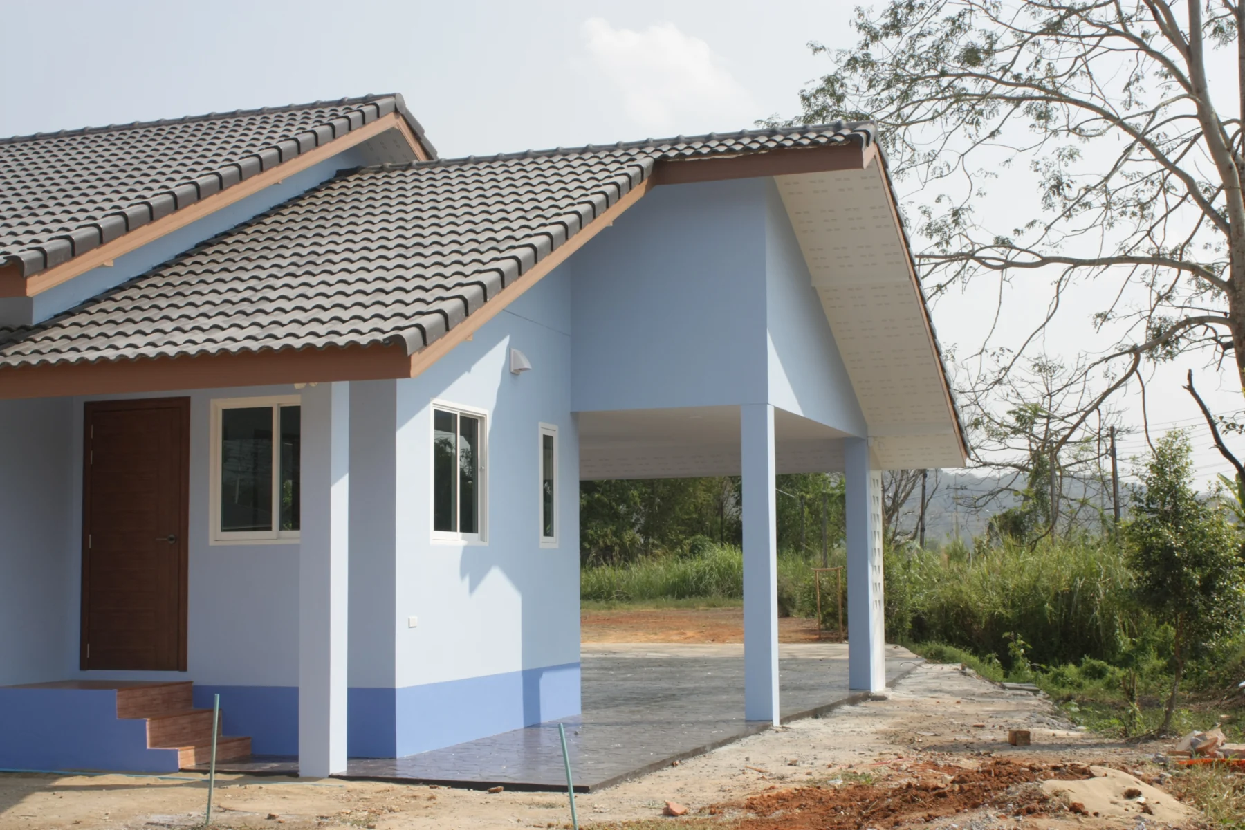 บ้านชั้นเดียวหลังคาจั่ว ผนังฟ้าขาว พร้อมโรงจอดรถ บ้านคุณยศ เชียงแสน