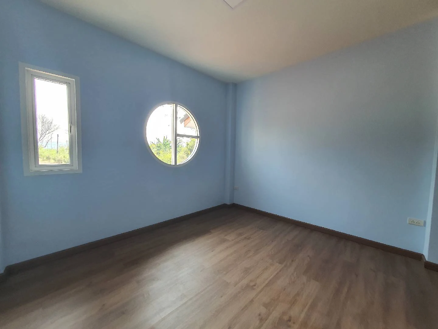 ห้องพักพื้นโทนไม้กับหน้าต่างวงกลม